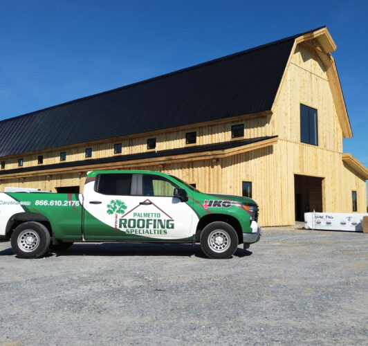 Palmetto Roofing Specialties truck in front of roof installation project in Asheville, NC